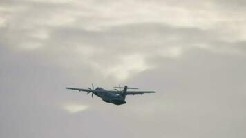 pasajero turbohélice aeronave partida, posterior vista. avión tomando apagado y escalada en cielo a nublado día. video