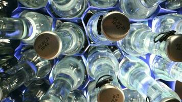oben Aussicht von Glas Flaschen und Metall Kappen mit Mineral Wasser platziert im Blau Plastik Behälter. video
