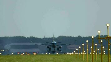 Rear view of an airplane braking after landing with smoke. Landing lights illuminate the runway. Cinematic footage of aircraft flight arrival video