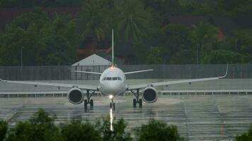 Passenger airliner on the tarmac in rainy gray weather. The rainy season in Phuket, Thailand. Tourism and travel concept video