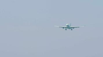 Jet commercial aircraft approaching landing, front view. Passenger plane flies at gray sky. Tourism and travel concept video