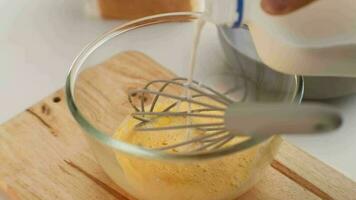 Woman beating eggs in a glass bowl. Young woman cooking in the kitchen. video