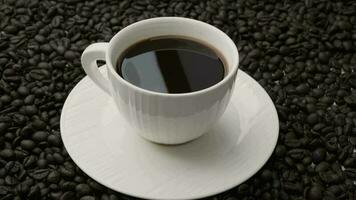 Hand halten Kaffee Rühren Löffel im Weiß Tasse auf Tisch. schwarz Kaffee im Weiß Tasse isoliert auf Hintergrund von geröstet Kaffee Bohnen. video