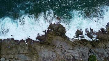 Aerial view of sea waves crashing on rocks cliff in the blue ocean. Top view of coastal rocks in Phuket ocean. Landscape view point of Laem Phromthep Cape in the morning. video