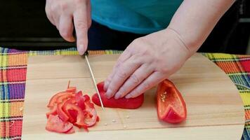 senior caucasian woman cut sweet red bell pepper on wooden cutting board video