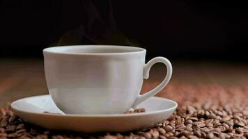 Dampf steigt an von ein heiß Tasse von Kaffee gegen ein Hintergrund von geröstet Kaffee Bohnen video