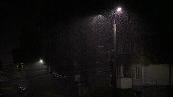 Double led panel lamppost under heavy rain at night. Midsize view of raindrops against a lamppost bright light. video