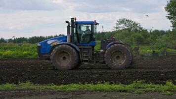 Blau Neu Holland Traktor mit doppelt Räder ziehen Egge beim Frühling Tag mit schleppend Bewegung video