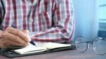 Cerca de la mano del hombre escribiendo en el bloc de notas video