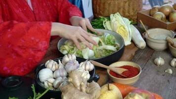 asiático mujer vistiendo coreano tradicional disfraces hanbok son aspersión sal por mano y kimchi ingredientes con ingredientes tal como ajo, gochugaru coreano chile, Fresco vegetales. video
