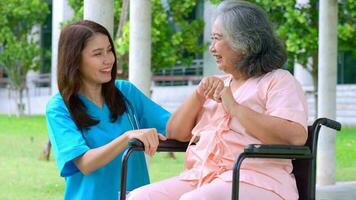 asiatisk omsorgsgivare eller sjuksköterska som tar hand om den äldre asiatiska patienten i rullstol. begreppet lycklig pensionering med omsorg från en vårdgivare och sparande och senior sjukförsäkring. äldreomsorg video