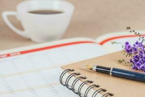 personal organizador o planificador con fuente bolígrafo y caliente café en madera mesa. foto
