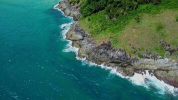 Aerial view of sea waves crashing on rocks cliff in the blue ocean. Top view of coastal rocks in Phuket ocean. Landscape view point of Laem Phromthep Cape in the morning video