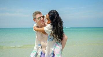 una pareja se abraza y se besa en la playa en sus vacaciones de verano y sonríen y están felices de vacaciones. foto