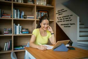 Female college student studying and working online with laptop and tablet at home photo