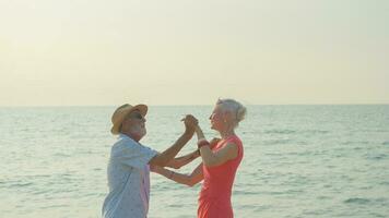 Two elderly men and women dancing at the beach on their summer vacation and they smile and enjoy their day off. photo