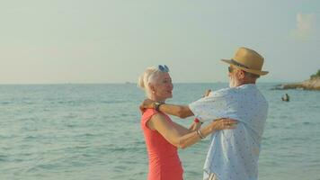 Two elderly men and women dancing at the beach on their summer vacation and they smile and enjoy their day off. photo