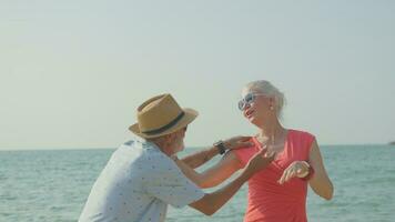 An elderly couple hugs their shoulders at the beach on their summer vacation and they smile and enjoy their vacation. photo