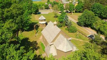 Young lithuanians relax by St. Joseph Church in Paluse, Lithuania. Stave Churches in Europe. Old heritage sites. Walls formed by vertical wooden boards. video