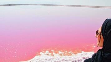 puesto turístico de mujer caucásica en la orilla del lago salado rosa maharlu. destino de viaje irán en shiraz video