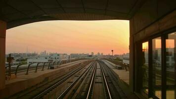 Dubai, VAE - - 10 .. Oktober, 2022 - - Metro Zug auf Eisenbahn ankommen zu Bahnhof im Dubai Stadt mit Sonnenuntergang Orange Himmel Hintergrund video