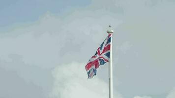 real União jack bandeira do a Unidos reino em mastro de bandeira tremulando dentro a vento. Unidos reino bandeira vídeo acenando dentro vento do ótimo bretanha. Reino Unido Fora eu brexit. nacional bandeira do Reino Unido coroação. britânico bandeira video