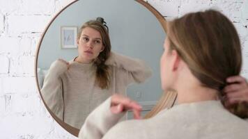 femme à la recherche à le miroir, fabrication en haut dans le Matin. Jeune millénaire femme Faire sa Matin routine à le chambre video