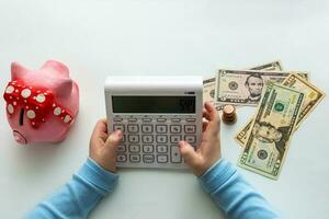 children's hands with calculator, money and piggy bank photo