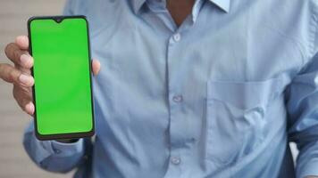 Cerca de la mano del hombre joven con un teléfono inteligente con pantalla verde video