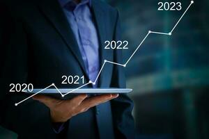 Man's hand pointing graph of success in 2022 year. Growing business concept photo