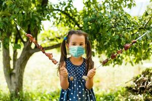 little girl in a protective mask spends summer holidays photo