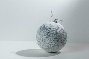 White Glitter Covered Christmas Tree Bauble Hanging Over White Background. photo