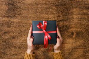 Man holding Christmas presents laid on a wooden table background photo