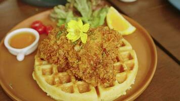 4k video, homemade fried chicken waffle with tomato, lemon and salad served with honey or maple syrup. breakfast, Breaded chicken on waffles with butter and syrup video