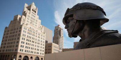 A statue of man with helmet sits in front of building photo