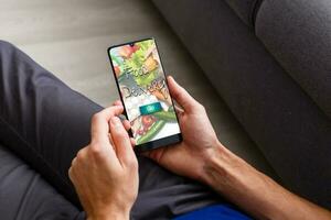 Man ordering take away food by internet with a smartphone while lying at home. photo