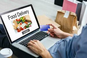 Man ordering take away food by internet with a laptop while lying at home. photo