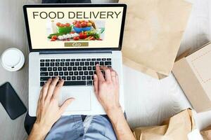 Man ordering take away food by internet with a laptop while lying at home. photo