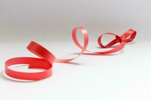 Shiny red satin ribbon on white background photo