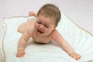 llorando bebé niña acostado en un pañal desnudo foto