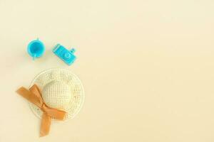 straw hat, toy camera and toy glass with a straw on a pale beige background, vacation content from copy space photo