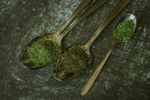 Spoons with spices and herbs on a black background. Food and cuisine ingredients. photo