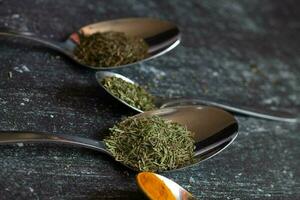 Spoons with spices and herbs on a black background. Food and cuisine ingredients. photo