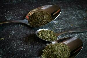 Spoons with spices and herbs on a black background. Food and cuisine ingredients. photo