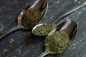 Spoons with spices and herbs on a black background. Food and cuisine ingredients. photo