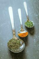 Spoons with spices and herbs on a black background. Food and cuisine ingredients. photo