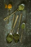 Spoons with spices and herbs on a black background. Food and cuisine ingredients. photo