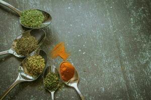 Spoons with spices and herbs on a black background. Food and cuisine ingredients. photo