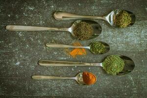 Spoons with spices and herbs on a black background. Food and cuisine ingredients. photo