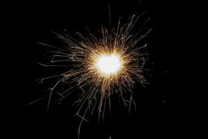 Burning sparkler isolated on black background. Fireworks theme. Light effect and texture. photo